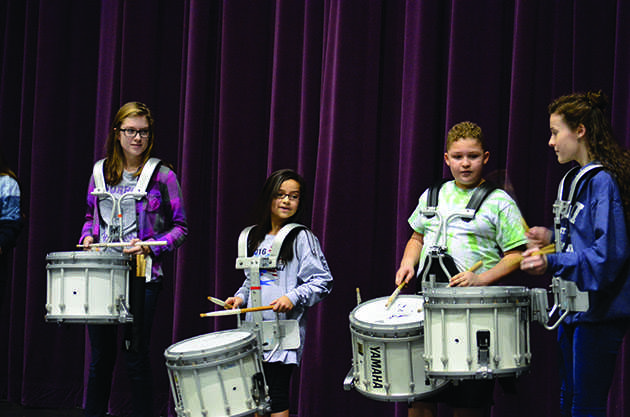Head snare players junior Cassandra Jennings (left) and senior Leinani Tadio (right) assist two fifth graders in a face-off drum battle presentation for their classmates. This competition opened up the program for the day, getting students excited and involved. “You don’t expect them to play well but a couple of them actually had tempo and they were trying really hard. It was really cool to see people who could be filling our spots in the next couple years,” senior drumline member Emily Anne Bray said.