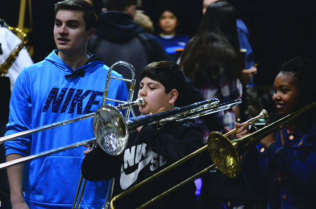 Junior trombone player Kevin West teaches two fifth graders the technique needed for producing sound from a trombone. At the end of each day fifth graders were selected from the crowd to come up and spend a few minutes with the high school musicians and their instruments. “You know that they don’t really care about what instrument they get they just want to be up on stage, but they’re so enthusiastic about just making a sound. There’s little things you get to use with the kids that you don’t get to use with older kids. [Such as], trying to get them to buzz their lips; remember when you tried to make horse noises when you were little? That works, these cute little things you don’t get to [use] with older kids because they’re too cool,” senior trombone player Brittany Villesvik said. 