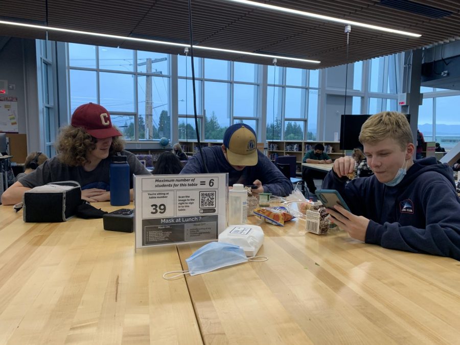 Looks like it's lunch time: Sophomores Colin Raynor, Jamison Lackor and Aidan Seals sit socially distanced at lunch in the Learning Commons.  Students are allowed to take their masks off while actively eating and/or drinking. At this table, a maximum of six people are allowed. They must sign in to allow contact tracing to occur. "It's an okay set-up, could be better," Lackor said.