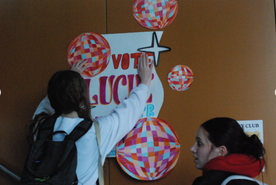 Creative campaigns: Juniors Mackenzie Conniff (left) and Lucie Grimes (right) post promotional posters around the school. ASB officer candidates worked hard to stand out from their competition.
