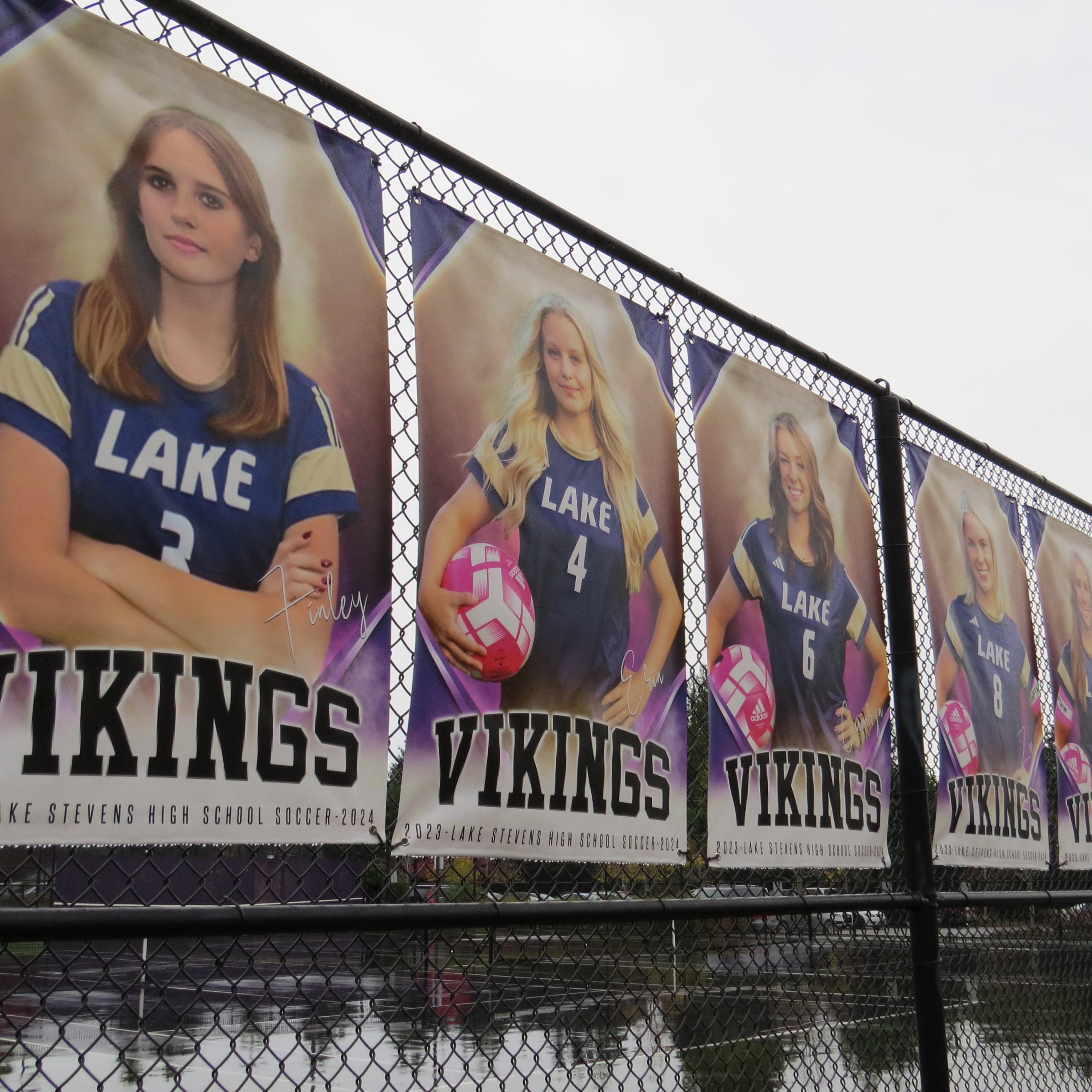 Senior photos of girls soccer players line the fencing at the LSHS Stadium.