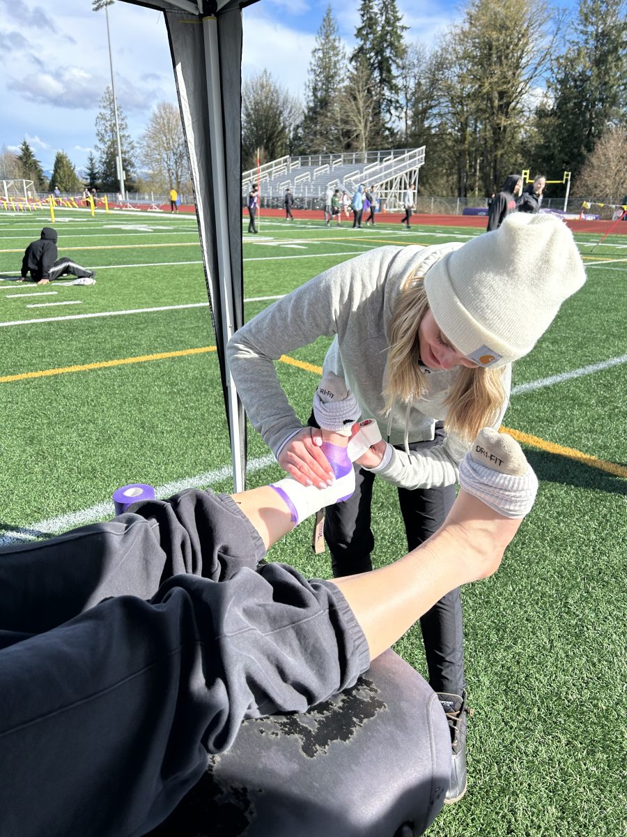 Ankle Stability: Head athletic trainer Mariah Luedtke tapes a track athlete's ankles to give more stability and prevent injuries.