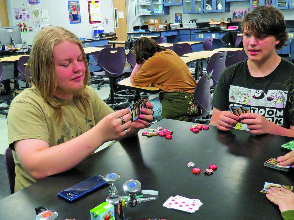 Students play a tense game in Tabletop Club. Three students play a lesser known game with cards and bottle caps. Most club members were not in the classroom for this photo. "Join Tabletop Club," the club's Vice President Jake Li said.