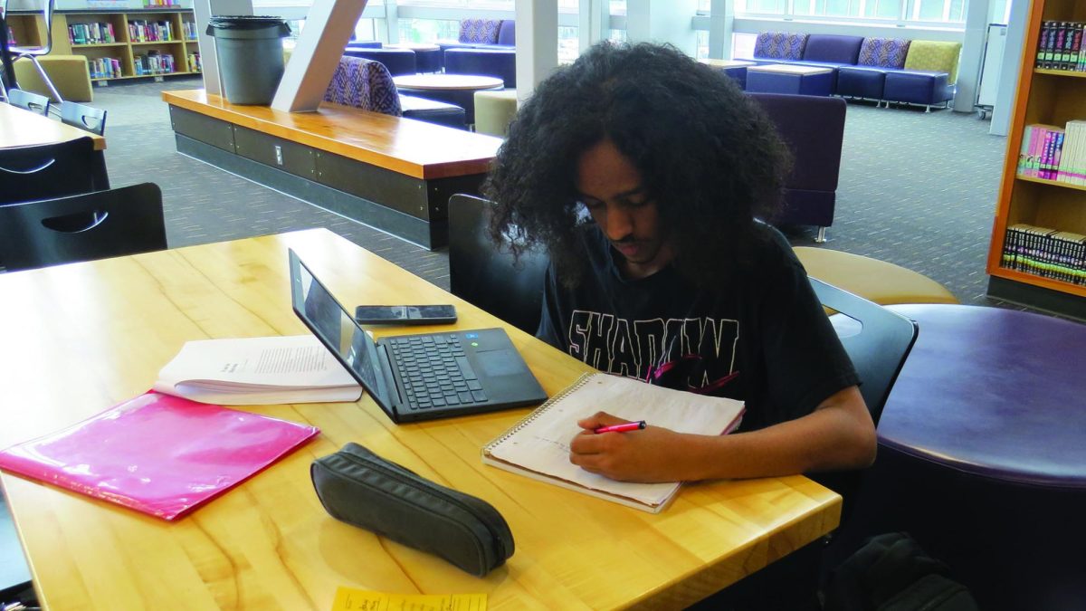 Josiah Asnake jots down notes in the library.