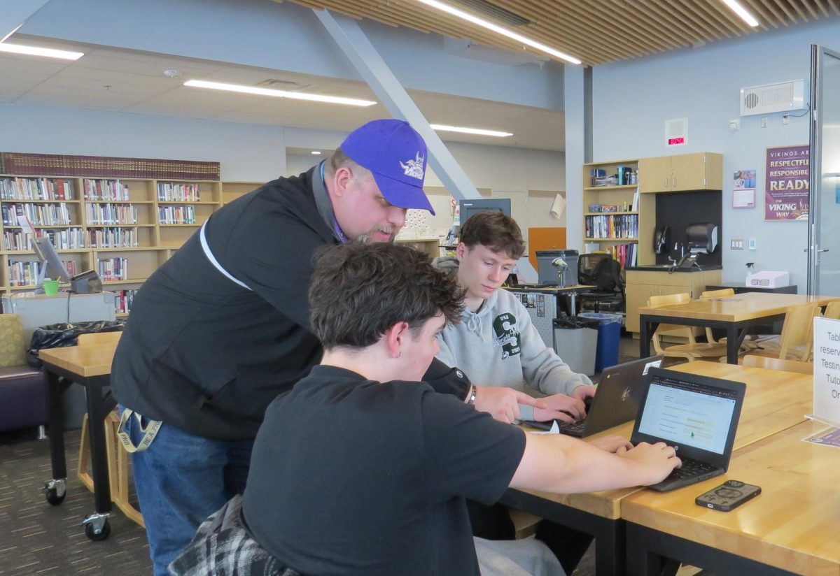 Mr. Matz assists junior Evan Graham and junior Trevor Coan with their science assignment.
